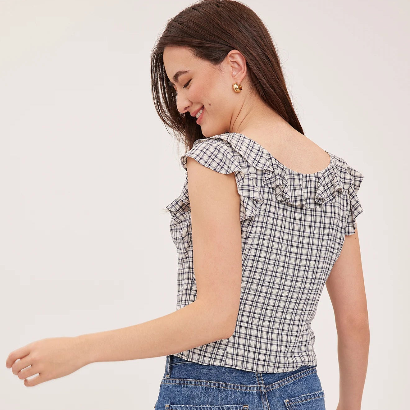 Woman wearing a checkered top and blue jeans on a white background