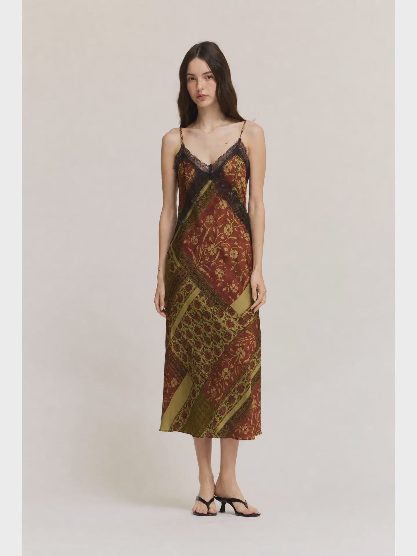 Gia midi satin slip dress featuring an abstract geometric print in olive green, cream, and red-brown tones, with lace trim, V-neckline, and adjustable straps.