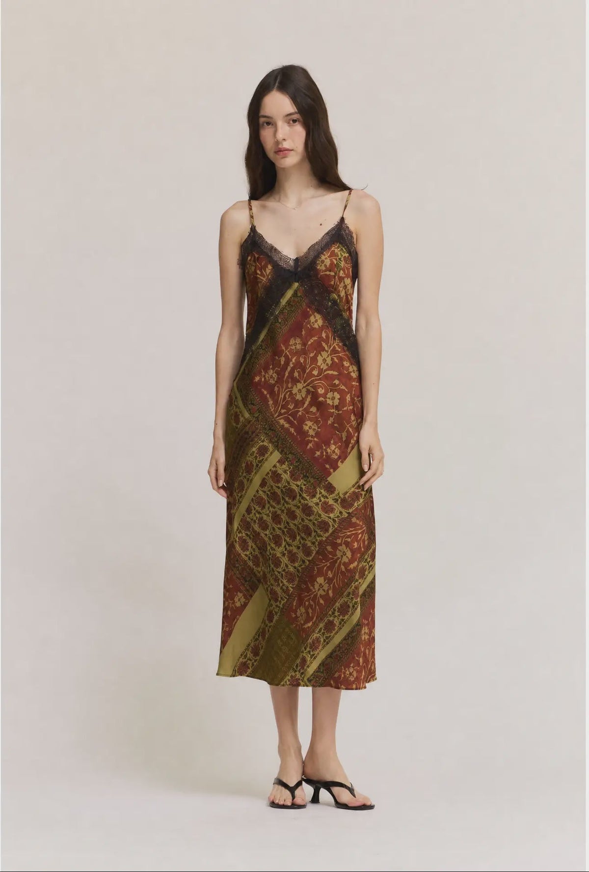 Gia midi satin slip dress featuring an abstract geometric print in olive green, cream, and red-brown tones, with lace trim, V-neckline, and adjustable straps.