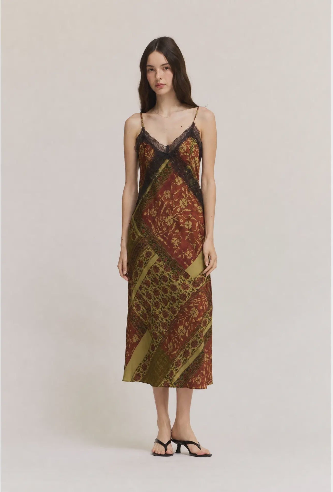 Gia midi satin slip dress featuring an abstract geometric print in olive green, cream, and red-brown tones, with lace trim, V-neckline, and adjustable straps.