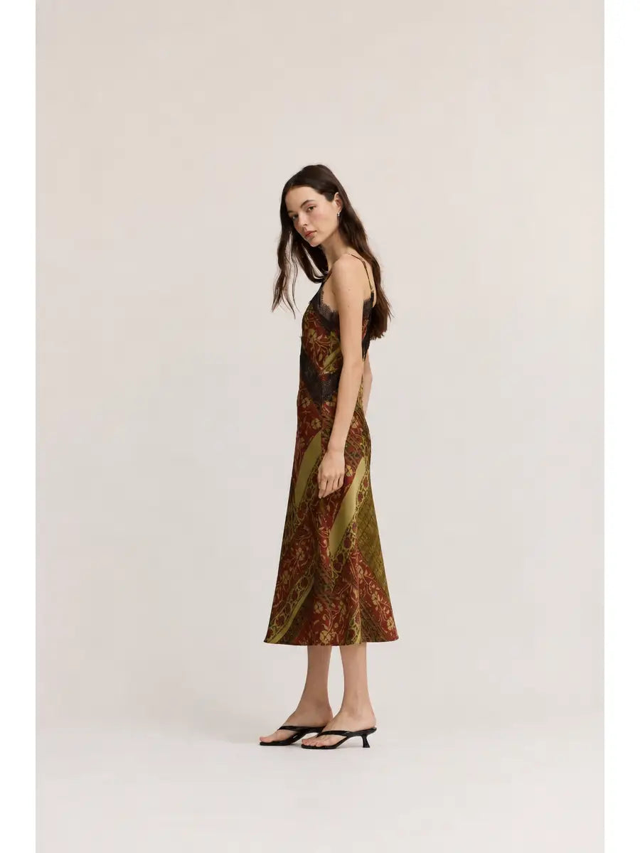 Gia midi satin slip dress featuring an abstract geometric print in olive green, cream, and red-brown tones, with lace trim, V-neckline, and adjustable straps.