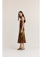 Gia midi satin slip dress featuring an abstract geometric print in olive green, cream, and red-brown tones, with lace trim, V-neckline, and adjustable straps.