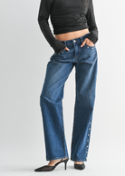 Woman wearing a black off-shoulder top and blue jeans on a white background