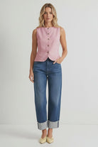 Light pink sleeveless woven vest featuring a round neckline, button-front closure, curved hem, and a tailored fit. Designed with an adjustable tie-back detail for a flattering, customizable silhouette