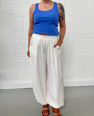 Person wearing a blue tank top and white balloon pants 