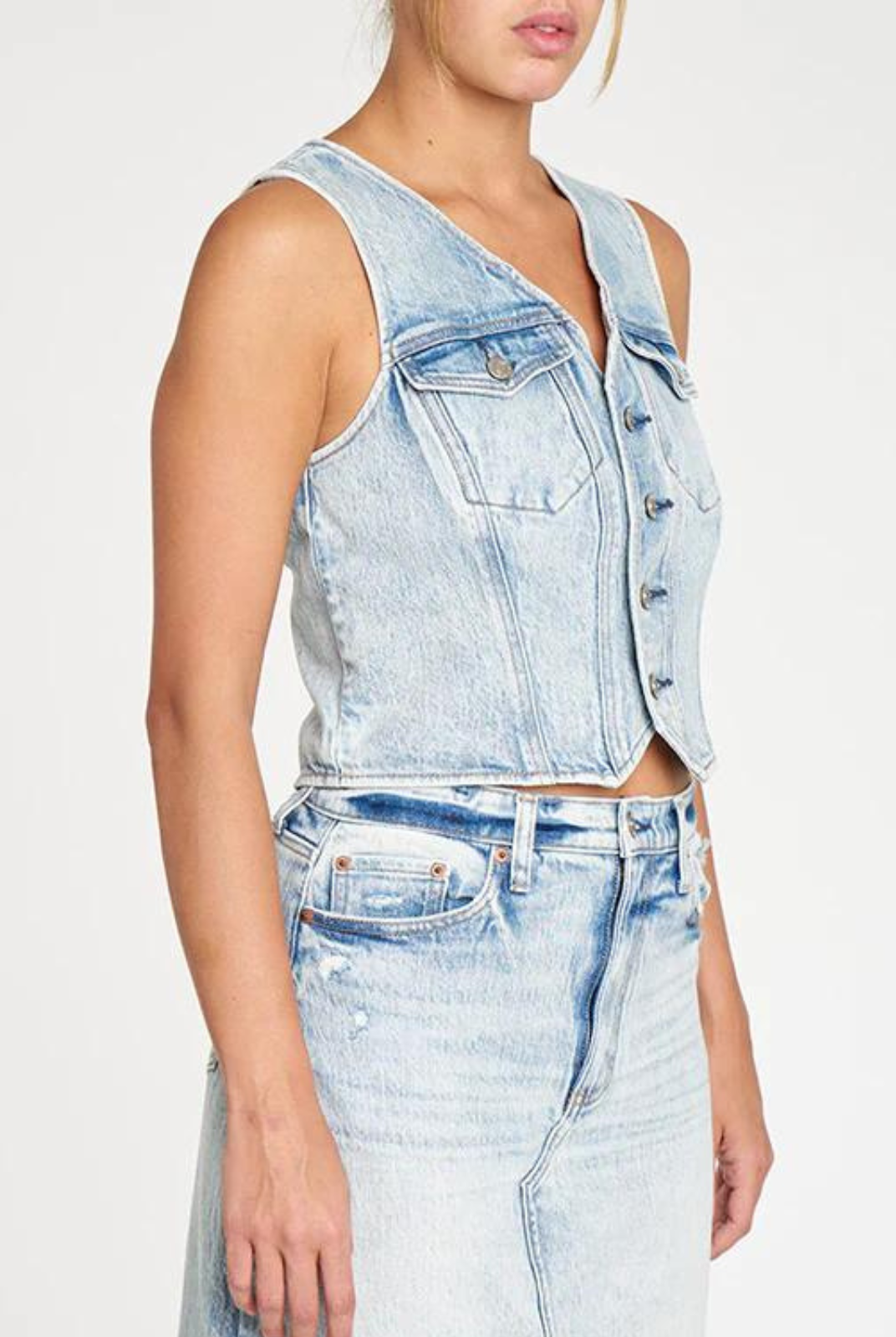 Daze Kiss Denim Vest. The Kiss is a fitted vest with front seam detailing and double chest pockets. In a light wash with distinct highs and lows, it can be worn as a top with our ankle length denim skirt or layered over a tee.