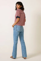 Light-to-medium blue high-rise jeans with a slim fit through the hips and thighs, subtle flared legs, classic five-pocket styling, and raw-cut hems.
