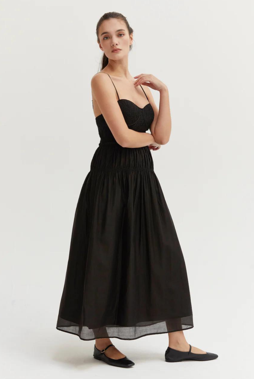 Lucy Tencel Blend Midi Dress- Black.Made with airy and semi sheer Tencel-blend, the Lucy Tencel Blend Midi Dress features smocked bustier with bra cup, adjustable spaghetti straps, side invisible zipper closure, and elasticized ruffle detail at waistline.