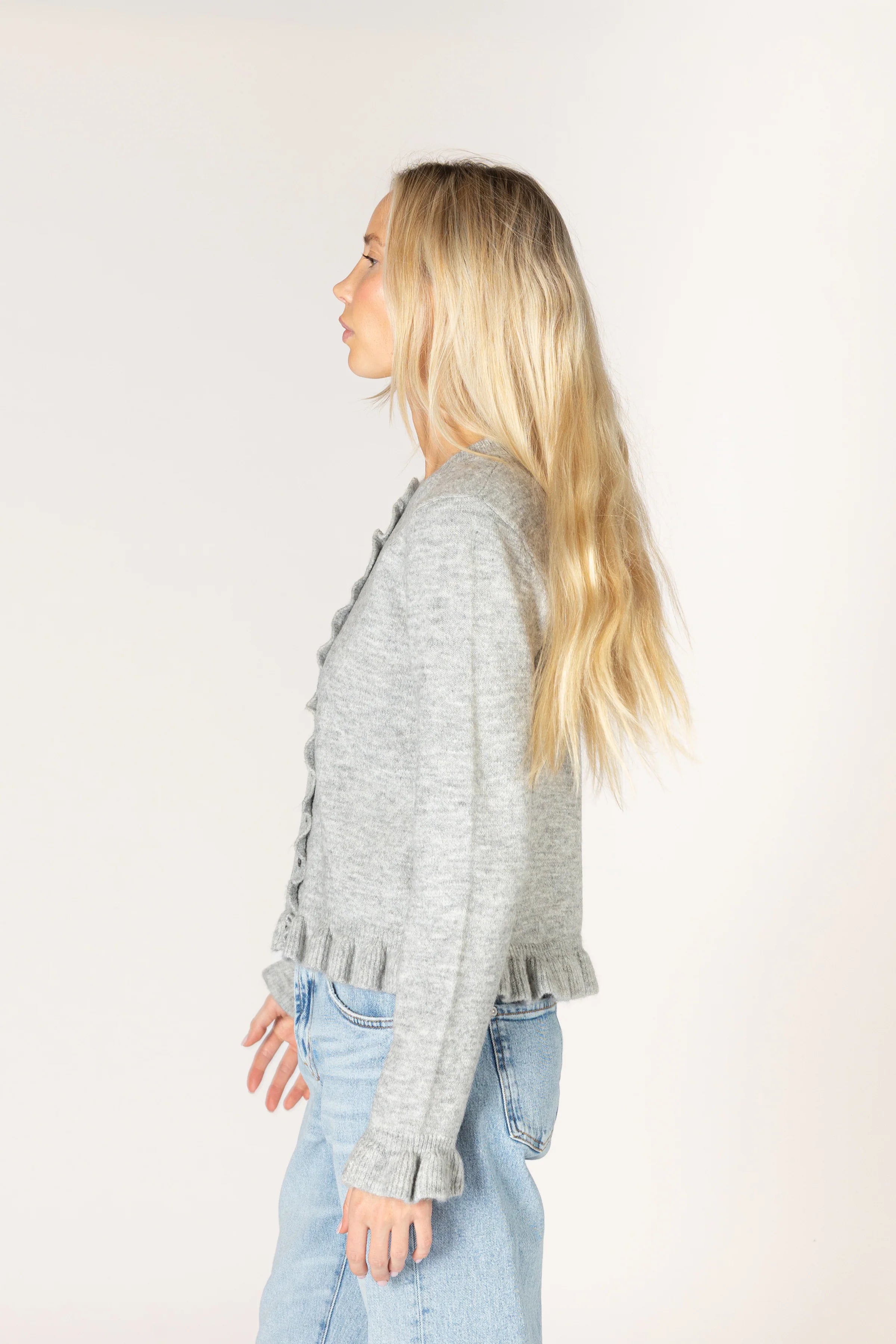 Sterling grey knit cardigan with a crew neckline and button-front closure, featuring delicate ruffle trim along the placket, hem, and cuffs.