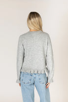 Sterling grey knit cardigan with a crew neckline and button-front closure, featuring delicate ruffle trim along the placket, hem, and cuffs.