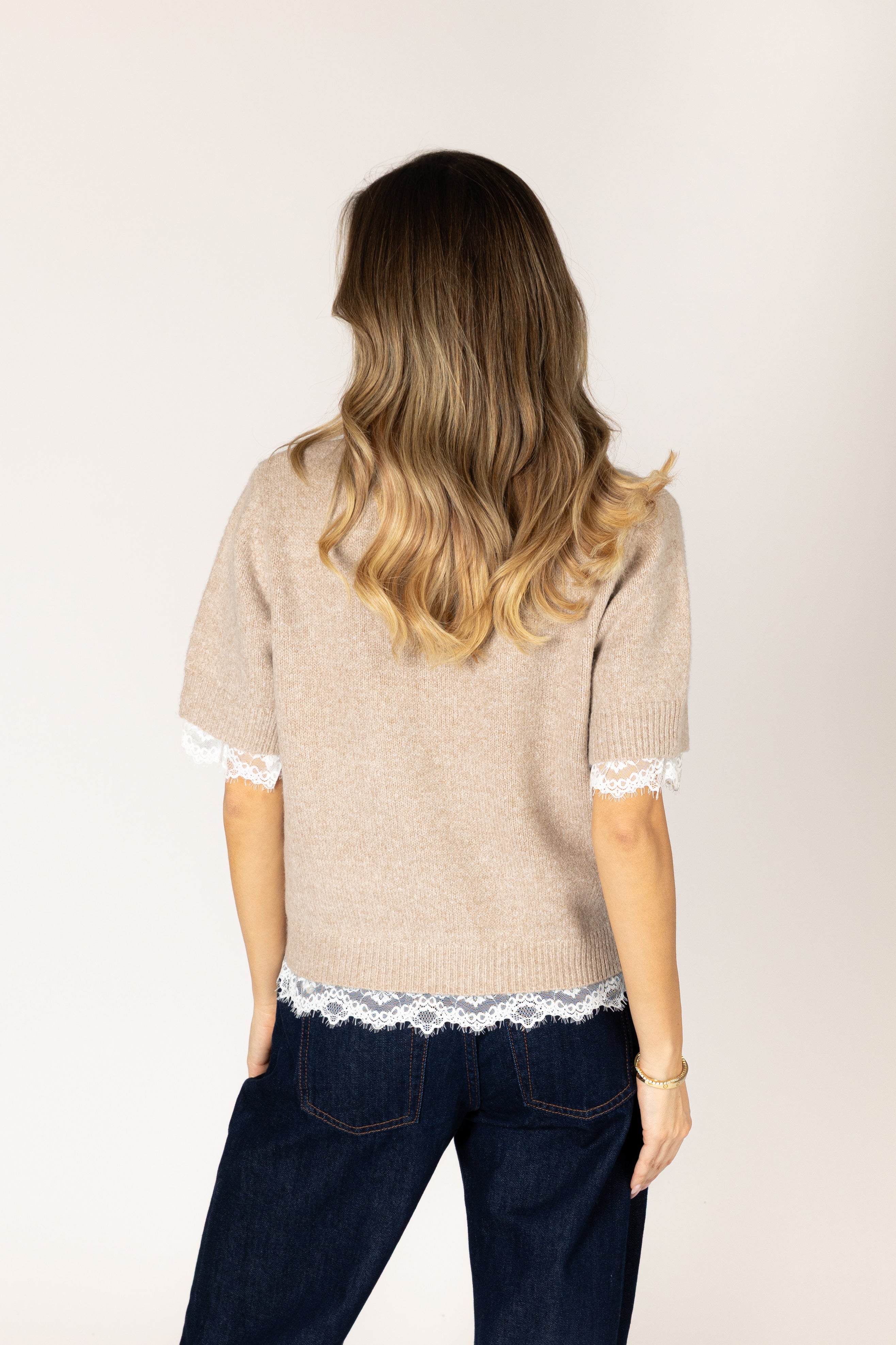 Lightweight knit sweater featuring a classic crew neckline, short sleeves, relaxed fit, and delicate lace trim at the sleeve cuffs and hem.
