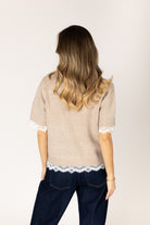 Lightweight knit sweater featuring a classic crew neckline, short sleeves, relaxed fit, and delicate lace trim at the sleeve cuffs and hem.
