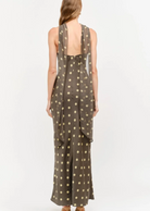 Make an unforgettable entrance in this stunning halter-neck midi dress. Showcasing a chic, classic polka dot motif against a rich, dark background, this piece features a sophisticated high neckline with a twisted halter strap detail that frames the shoulders to perfection. Cut in a sleek, fluid silhouette that gracefully skims the body, it offers an effortless blend of retro charm and contemporary style.&nbsp;
