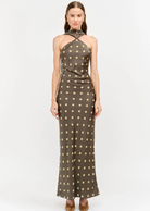Make an unforgettable entrance in this stunning halter-neck midi dress. Showcasing a chic, classic polka dot motif against a rich, dark background, this piece features a sophisticated high neckline with a twisted halter strap detail that frames the shoulders to perfection. Cut in a sleek, fluid silhouette that gracefully skims the body, it offers an effortless blend of retro charm and contemporary style.&nbsp;