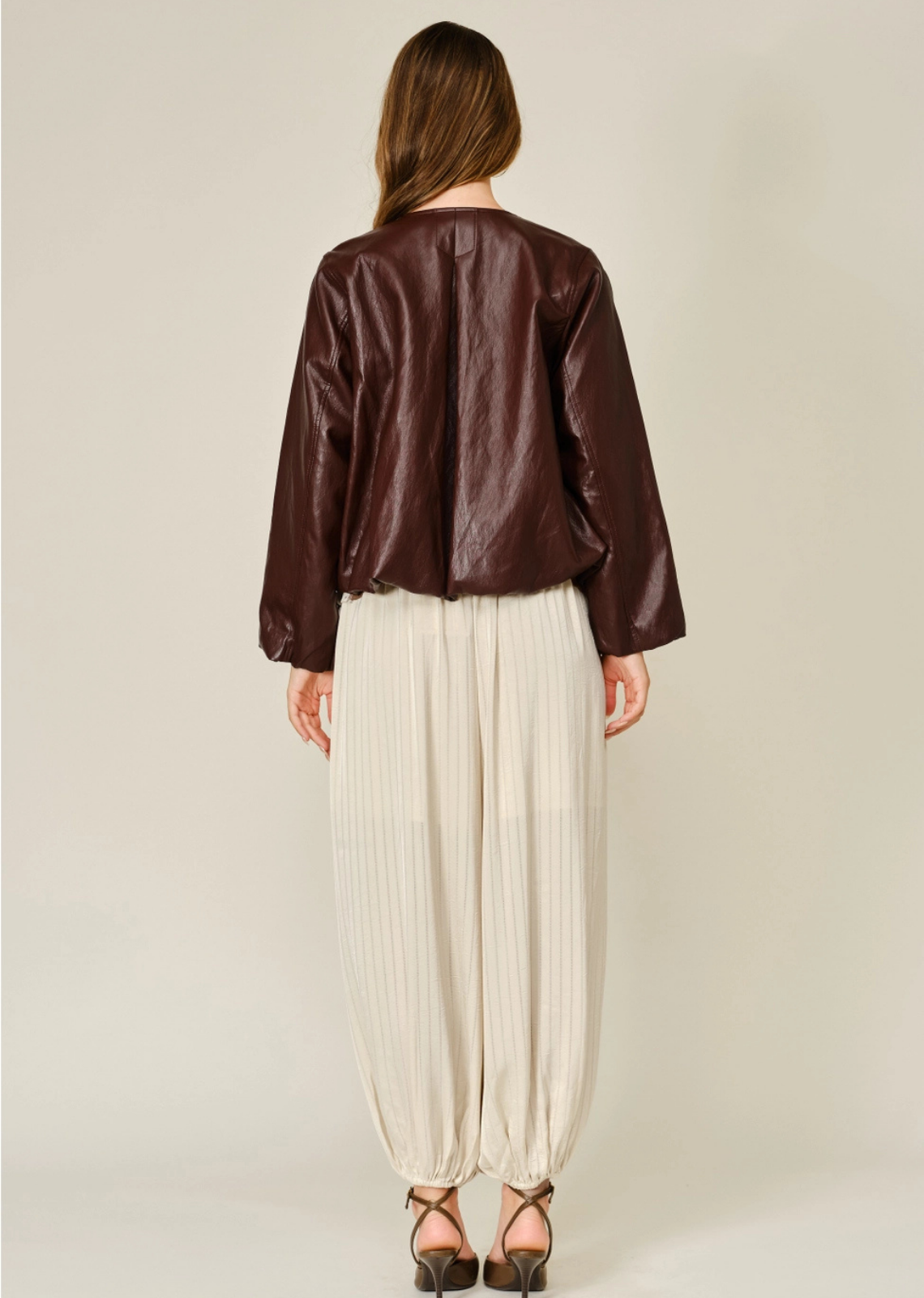 Merlot relaxed balloon bomber jacket in mahogany vegan leather, featuring a round neckline, front zip closure, pleated detailing, and elasticized cuffs and hem.