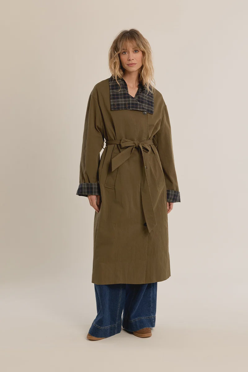 Long belted trench coat featuring a classic plaid lining, wide waist belt, front button closure, and side patch pockets.