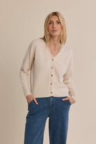 Short knit cardigan featuring long sleeves, a delicate lace-trimmed V-neckline, and classic full-length button-front closure.