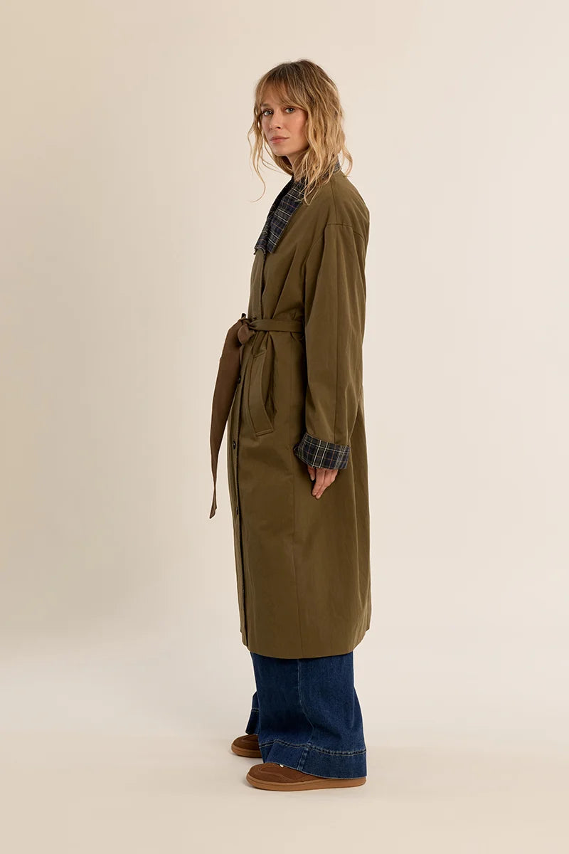 Long belted trench coat featuring a classic plaid lining, wide waist belt, front button closure, and side patch pockets.