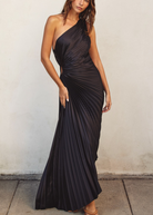 Woman wearing a black one-shoulder dress against a plain background