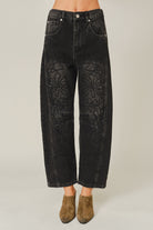 Women’s washed black barrel jeans featuring tonal floral embroidery, high-rise waist, five-pocket styling, relaxed curved leg, and cropped ankle-length fit.
