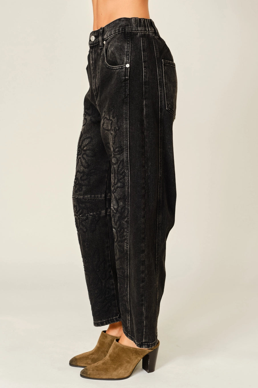 Women’s washed black barrel jeans featuring tonal floral embroidery, high-rise waist, five-pocket styling, relaxed curved leg, and cropped ankle-length fit.