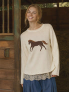 Women’s cream horse knit pullover featuring a relaxed fit, long sleeves, dropped shoulders, and western-inspired horse graphic. Lace under shirt shown is not included.