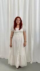 Woman wearing a white dress with light taupe stripes, soft puff sleeves and a button down detail
