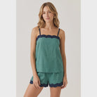 Green linen-blend tank top featuring a cream scalloped neckline, braided adjustable spaghetti straps, a relaxed fit, and a lightweight woven finish. Designed with a back keyhole and button closure 