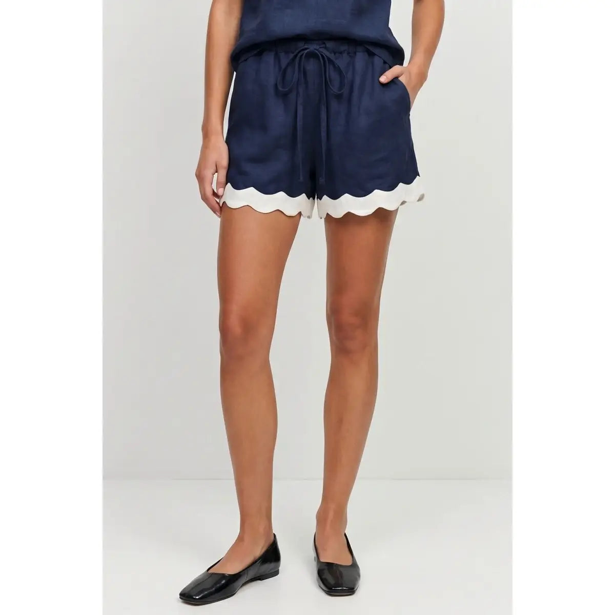 Navy linen-blend pull-on shorts featuring scalloped hems, side pockets, and a self-fabric drawstring waistband