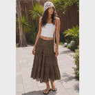 Model wearing The Savannah Lace Maxi Skirt, a brown crinkle maxi skirt featuring tiered ruffle panels, delicate lace trim, and a fitted waistband
