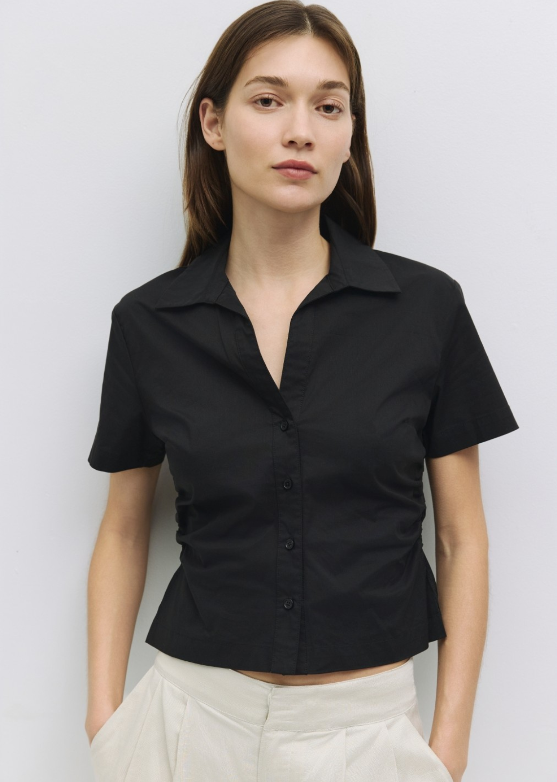 Woman wearing a black short-sleeve shirt against a white background