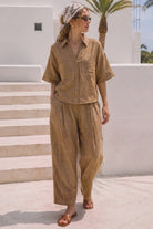 Women's brown linen blend wide leg pants with a relaxed fit, elastic waistband, side pockets, and contrast stitching.