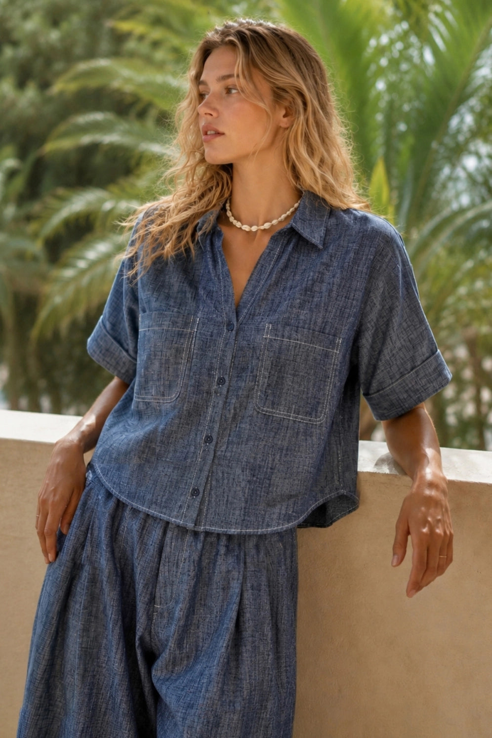 Women's denim blue linen blend camp shirt with a relaxed boxy fit, button-front closure, camp collar, oversized patch pockets, and contrast stitching.