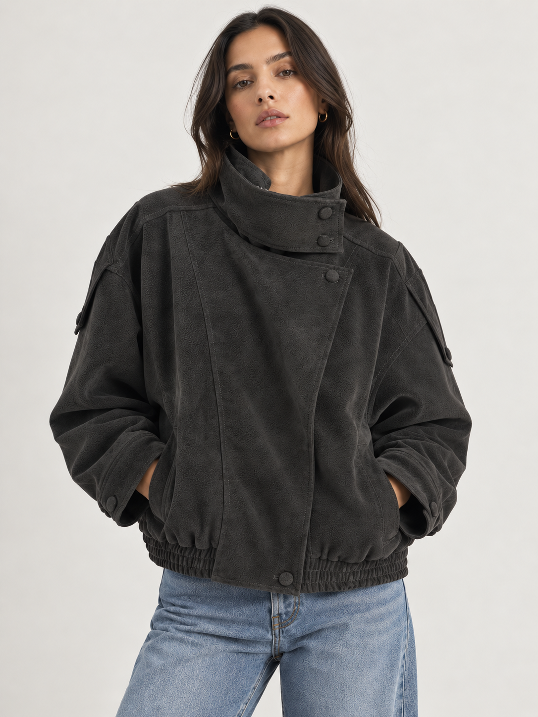 Model wearing the Tribeca Leather Bomber Jacket in black, featuring an oversized fit, high collar, asymmetrical front closure, tonal buttons, sleeve tab details, side pockets, and an elasticized hem.