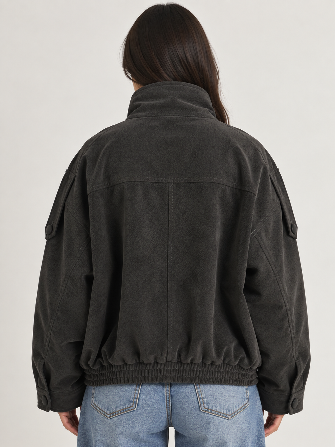 Model wearing the Tribeca Leather Bomber Jacket in black, featuring an oversized fit, high collar, asymmetrical front closure, tonal buttons, sleeve tab details, side pockets, and an elasticized hem.