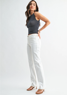 Woman wearing a black polka dot top and white pants on a white background