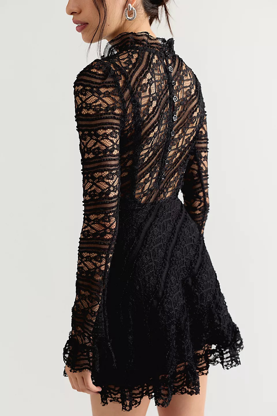 Romantic lace mini dress with an A-line silhouette, ruffled mock neckline, long sleeves, button-back closure, and removable slip lining.
