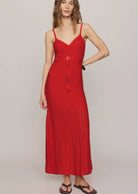 Woman wearing a red crochet dress with tassles against a plain background