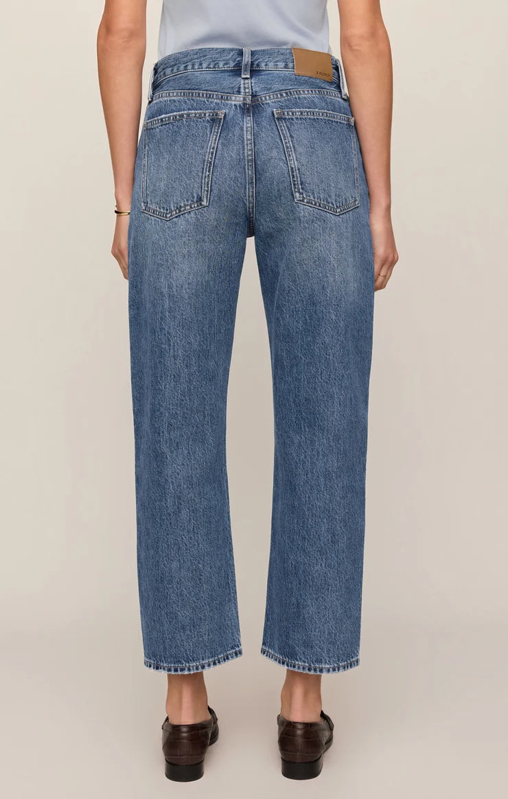 Vintage-wash blue mid-rise jeans featuring a relaxed bowed-leg silhouette, ankle-length hem, and classic five-pocket styling.

