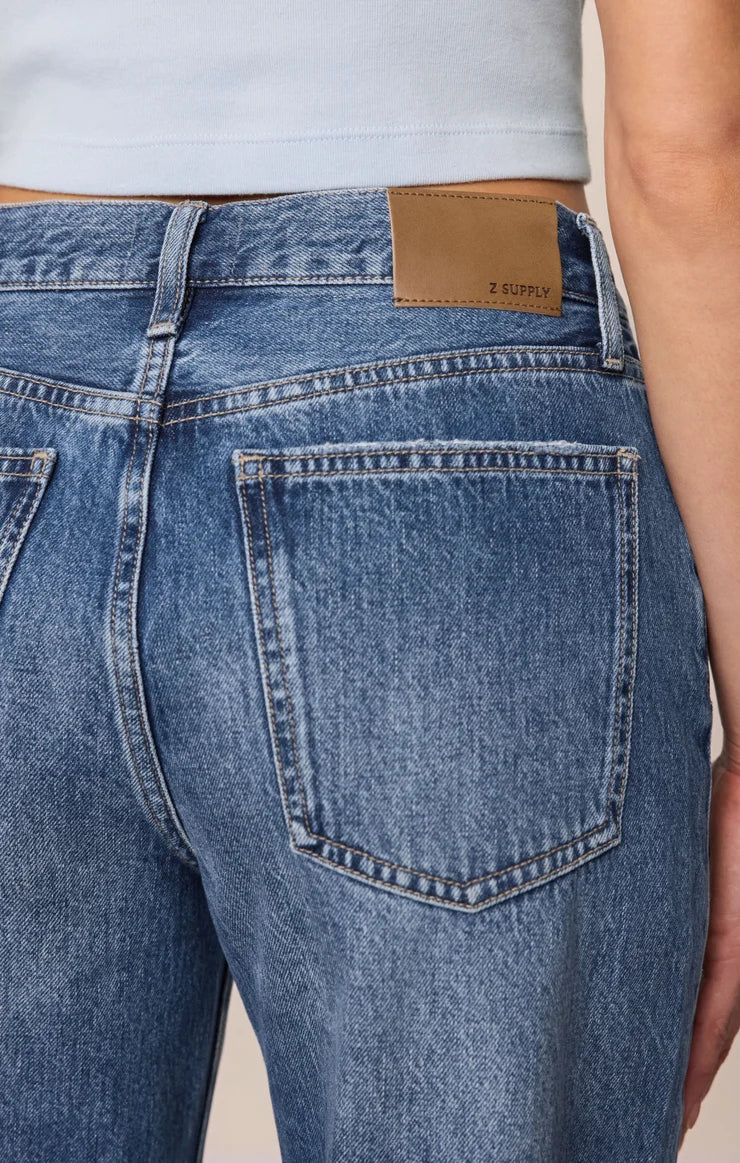 Vintage-wash blue mid-rise jeans featuring a relaxed bowed-leg silhouette, ankle-length hem, and classic five-pocket styling.
