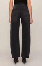 High-rise washed black jeans featuring a relaxed bowed-leg silhouette, full-length hem, and contrast whipstitch detailing inside the cuff.