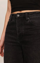 High-rise washed black jeans featuring a relaxed bowed-leg silhouette, full-length hem, and contrast whipstitch detailing inside the cuff.