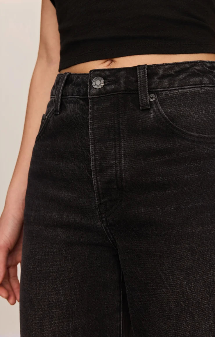 High-rise washed black jeans featuring a relaxed bowed-leg silhouette, full-length hem, and contrast whipstitch detailing inside the cuff.