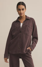Woman wearing a brown shirt and pants against a beige background