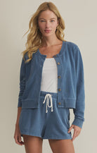 Woman wearing a blue denim cardigan and shorts set on a beige background