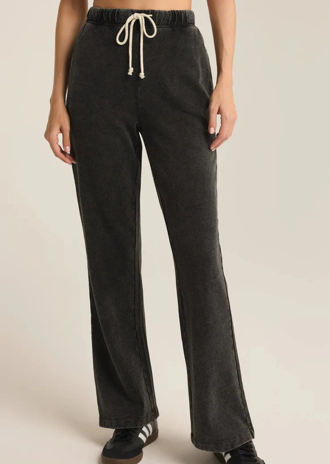 Dark gray sweatpants with a drawstring on a beige background