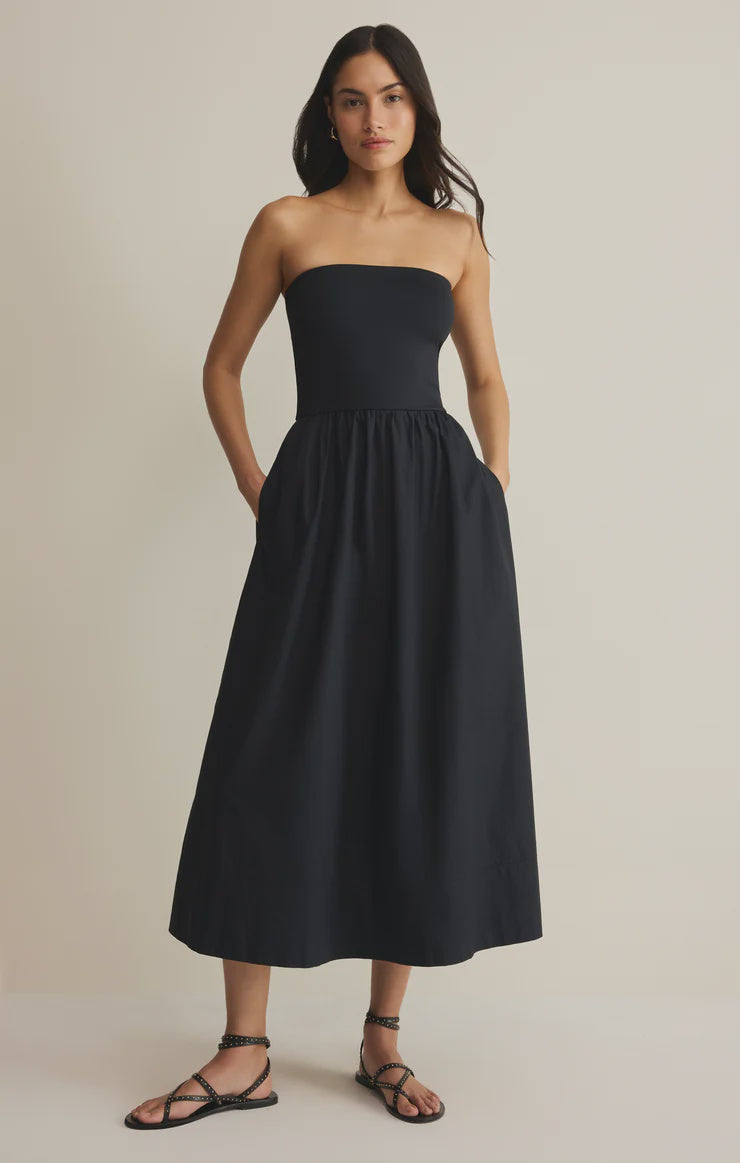 Woman wearing a black strapless dress against a plain background