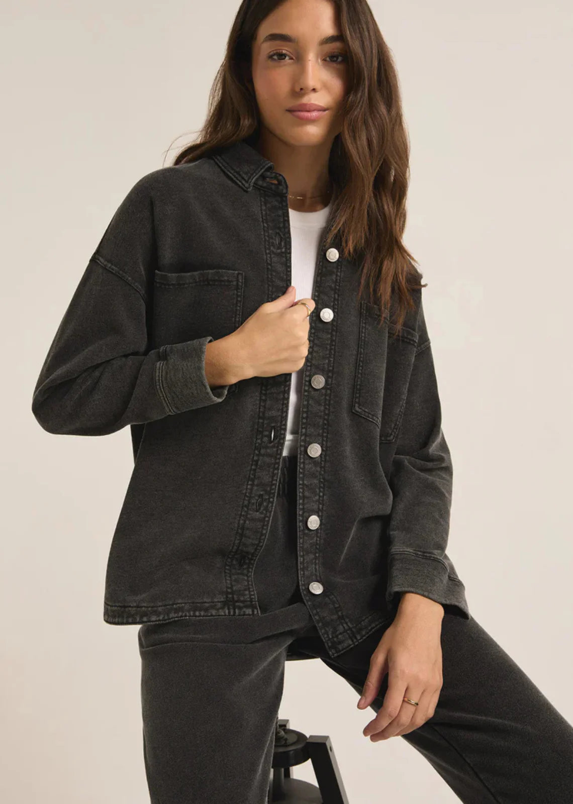 Woman wearing a black denim jacket on a plain background