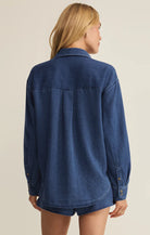 Person wearing a blue denim shirt on a beige background