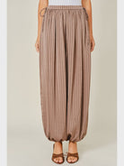 Zola Striped Satin Bubble Pants featuring a soft, glossy satin finish with a striped pattern, comfortable elastic waistband, adjustable drawstring side details, and functional side pockets. Designed with a relaxed, voluminous balloon silhouette and a flowy, lightweight feel for an effortlessly chic look.